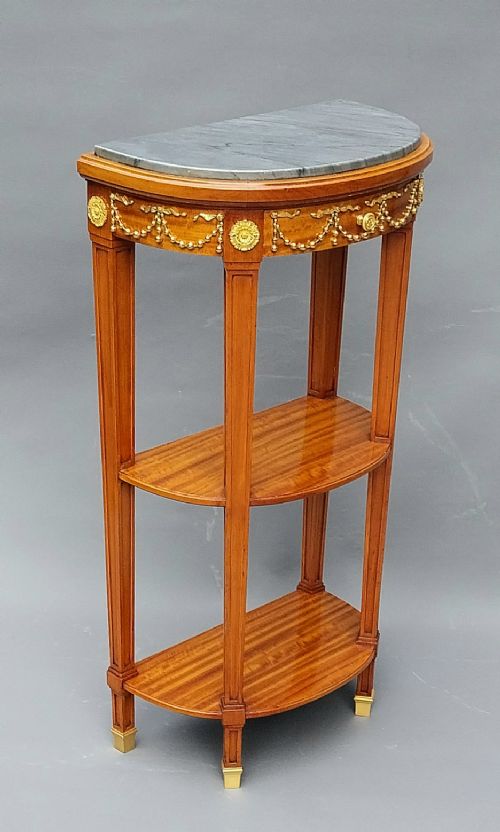 A pair of semi-circular French satinwood etagere tables featuring grey marble tops, gilt bronze garland mounts, and two lower tiers. View XI
