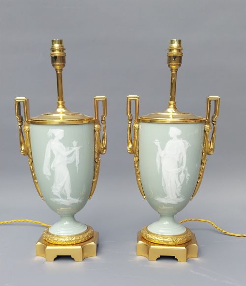 fig 3. A pair of 19th-century French celadon green porcelain urn table lamps featuring white pate-sur-pate classical relief figures, gilt bronze handles and bases, and cream pleated lampshades.