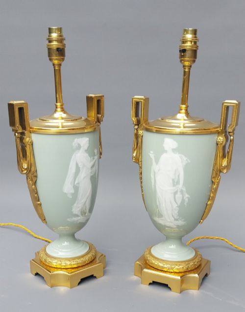 fig 4. A pair of 19th-century French celadon green porcelain urn table lamps featuring white pate-sur-pate classical relief figures, gilt bronze handles and bases, and cream pleated lampshades.
