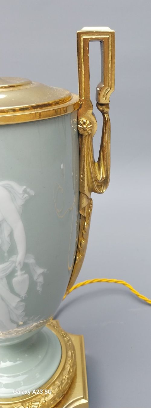 A pair of 19th-century French celadon green porcelain urn table lamps featuring white pate-sur-pate classical relief figures, gilt bronze handles and bases, and cream pleated lampshades. View VIII