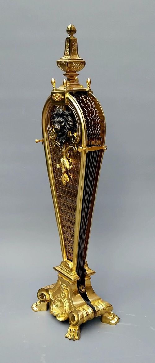 fig 2. A French gilt bronze fan-shaped fire screen featuring folding filigree mesh panels, an ornate central standard with a dark mask, and a cast shell pedestal base.