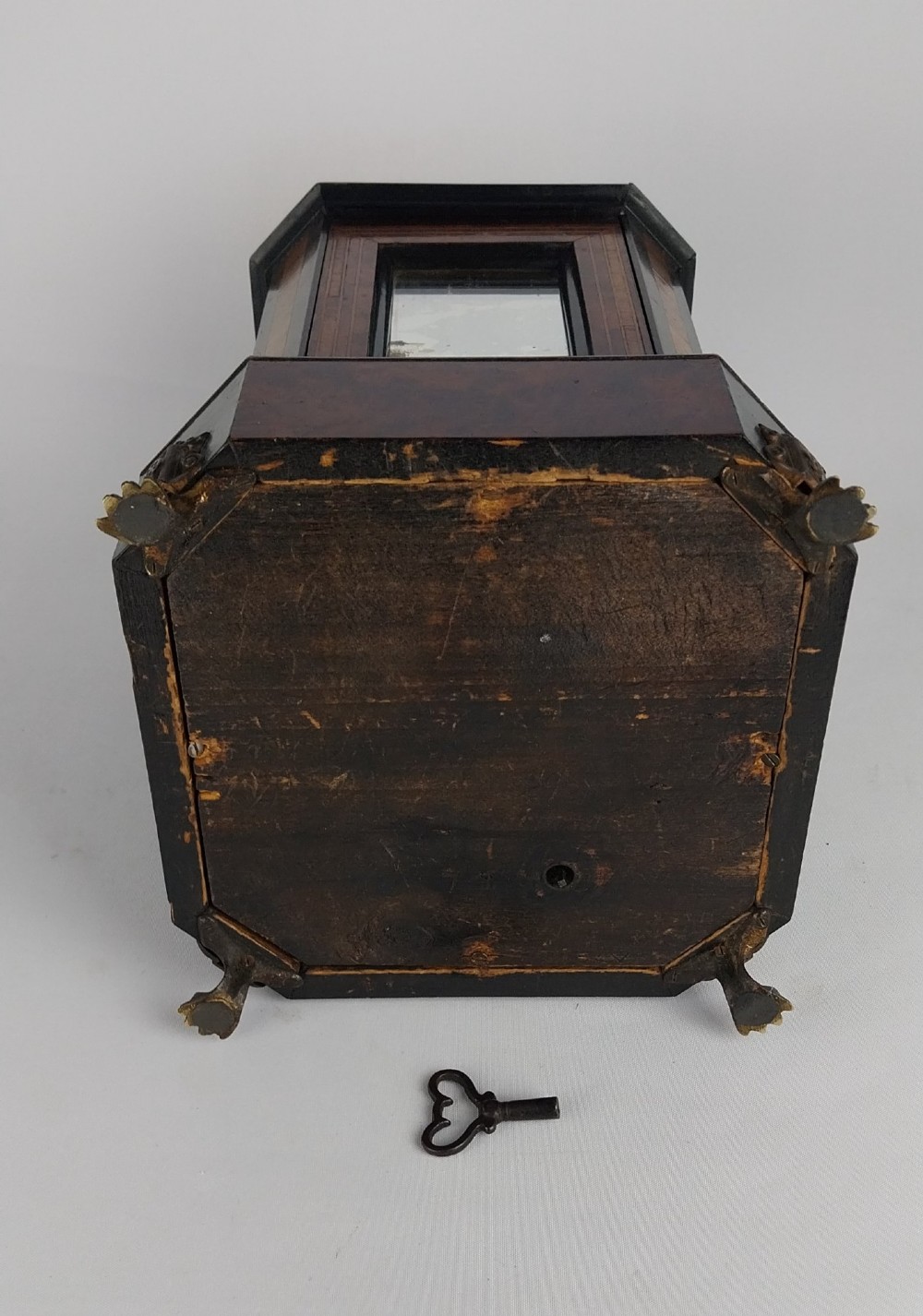 An upright Victorian hexagonal musical cigar box featuring ebonised wood, burr walnut panels, glass inserts, an ornate brass top handle, and brass claw feet. View IX