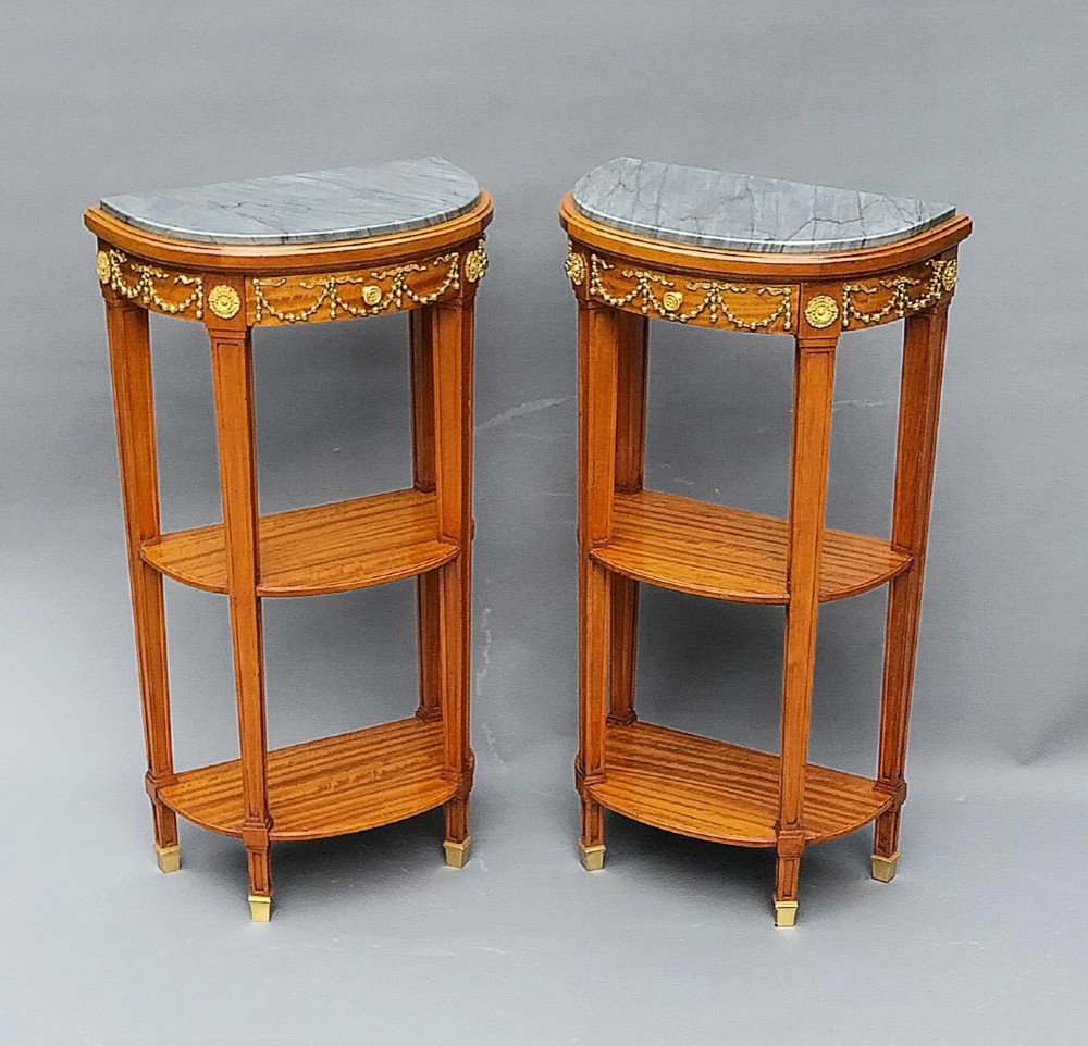 A pair of semi-circular French satinwood etagere tables featuring grey marble tops, gilt bronze garland mounts, and two lower tiers. View II