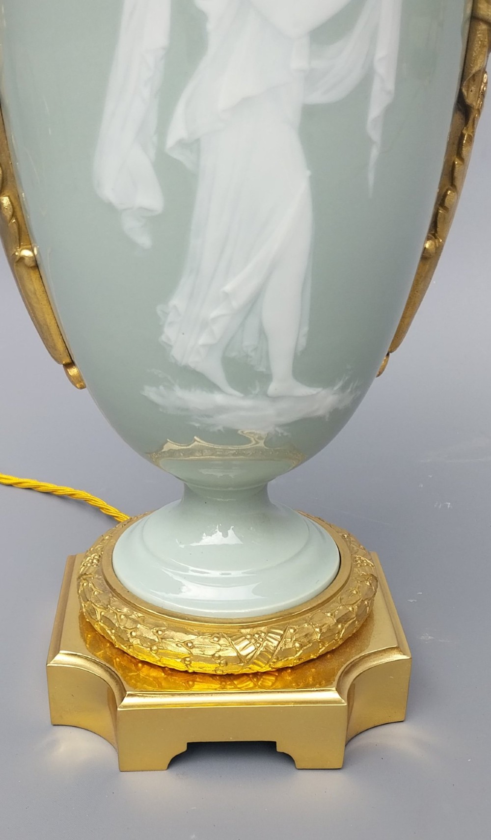 A pair of 19th-century French celadon green porcelain urn table lamps featuring white pate-sur-pate classical relief figures, gilt bronze handles and bases, and cream pleated lampshades. View XI