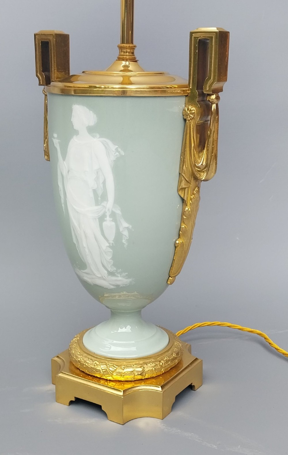 A pair of 19th-century French celadon green porcelain urn table lamps featuring white pate-sur-pate classical relief figures, gilt bronze handles and bases, and cream pleated lampshades. View XIV