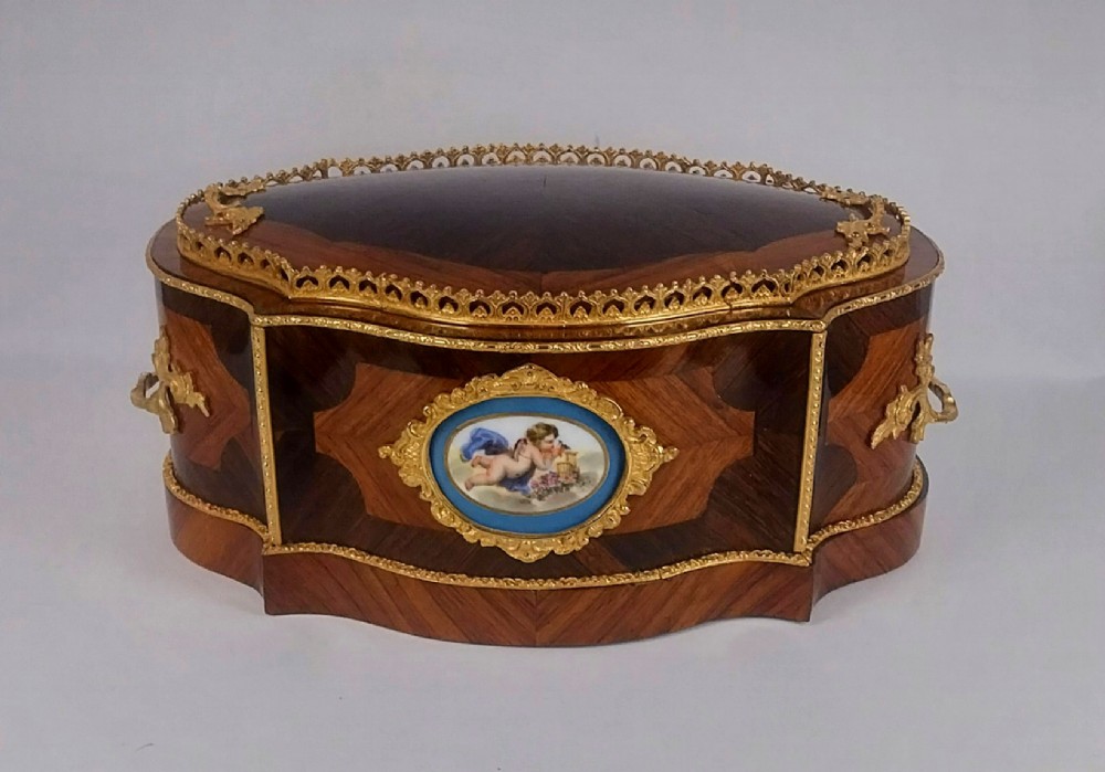 A late 19th-century French serpentine table jardiniere constructed from kingwood and tulipwood parquetry, featuring gilt bronze mounts and a central oval hand-painted porcelain medallion depicting a cherub.