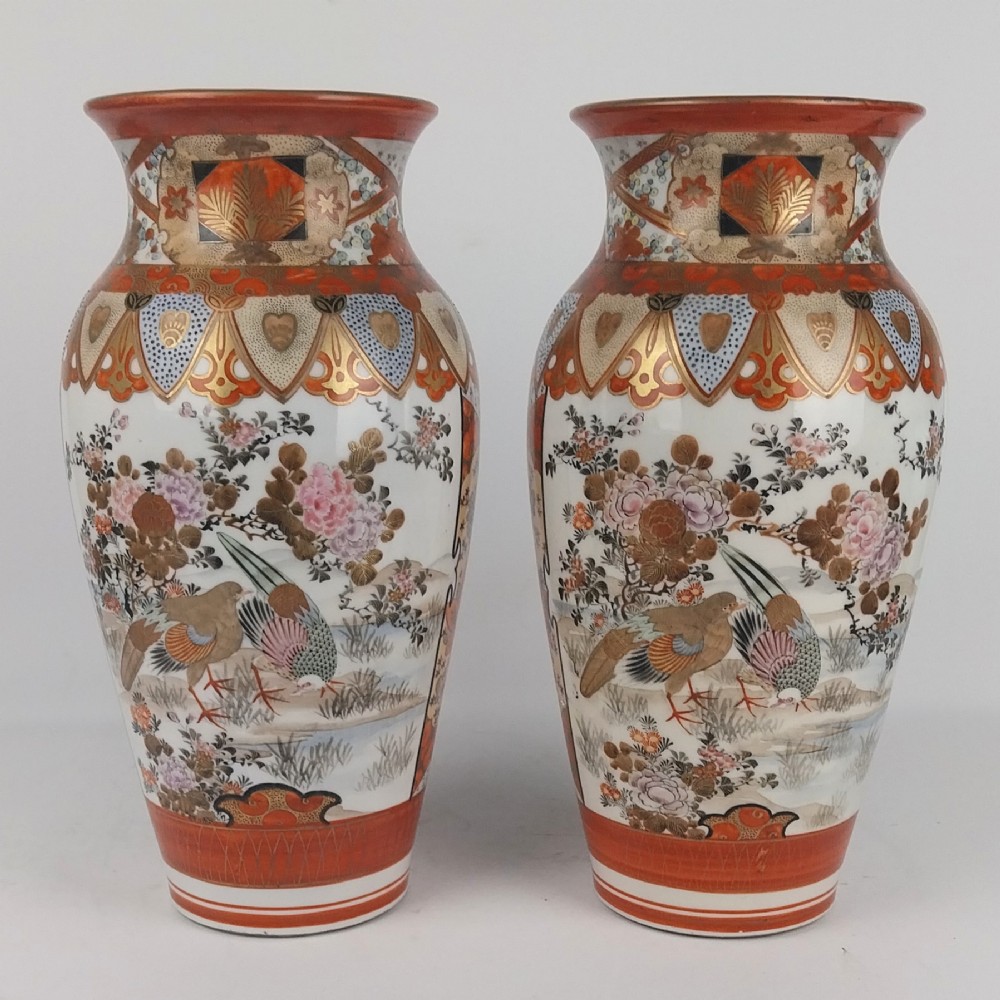 A pair of baluster-shaped Japanese Kutani porcelain vases decorated with hand-painted birds, flowers, iron-red panels, and gold accents.