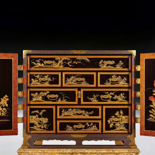 fig 3. A black Japanese lacquer cabinet with gold landscape designs and engraved brass lockplates, supported on an ornate carved French giltwood stand with cabriole legs.