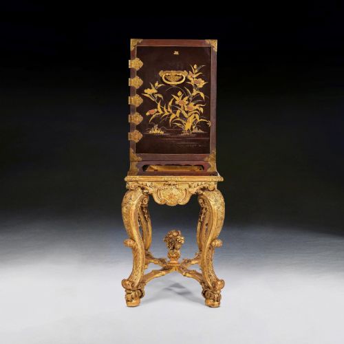 fig 4. A black Japanese lacquer cabinet with gold landscape designs and engraved brass lockplates, supported on an ornate carved French giltwood stand with cabriole legs.