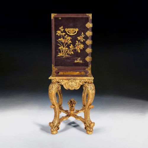 fig 5. A black Japanese lacquer cabinet with gold landscape designs and engraved brass lockplates, supported on an ornate carved French giltwood stand with cabriole legs.