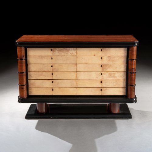 fig 1. An Art Deco palisander commode featuring twelve parchment-covered drawer fronts, ebonised side trim, curved timber flanks, and a stepped plinth base.