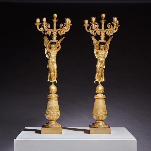 fig 1. A pair of French Empire gilt bronze candelabra featuring winged Victory figures supporting multi-arm candle holders on pedestals.