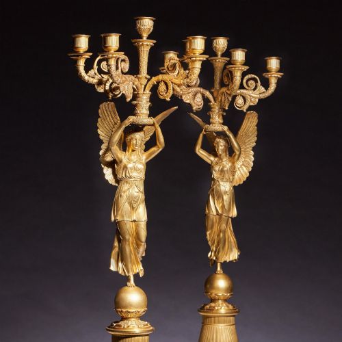 fig 3. A pair of French Empire gilt bronze candelabra featuring winged Victory figures supporting multi-arm candle holders on pedestals.