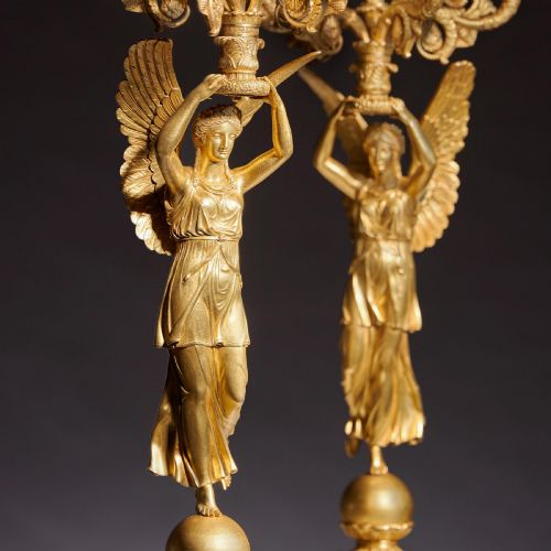 fig 4. A pair of French Empire gilt bronze candelabra featuring winged Victory figures supporting multi-arm candle holders on pedestals.