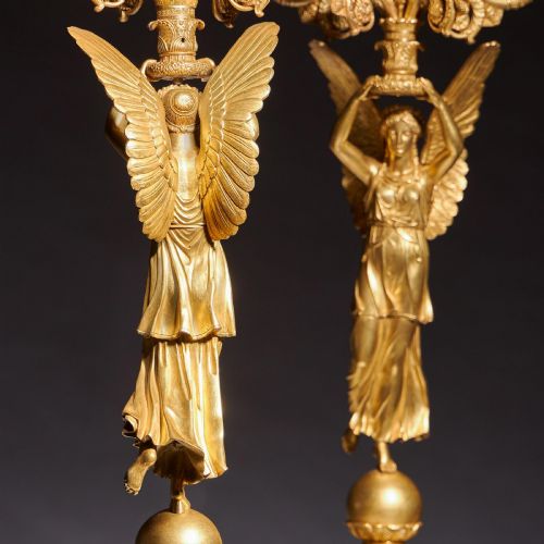 fig 5. A pair of French Empire gilt bronze candelabra featuring winged Victory figures supporting multi-arm candle holders on pedestals.
