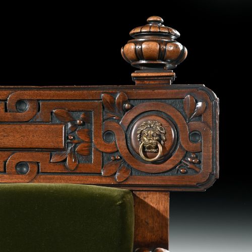 fig 4. A carved wood armchair with green velvet upholstery, winged lion head armrests, carved claw feet, and a decorated crest rail.