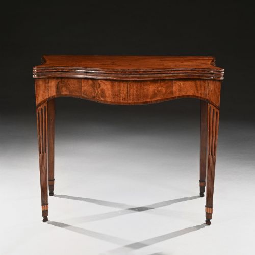 fig 1. A George III mahogany tea table featuring a serpentine fold-over top, fluted tapered legs, and flame mahogany veneers on the frieze.