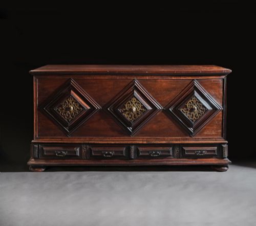 fig 1. A dark mahogany Portuguese colonial chest featuring three raised diamond-moulded panels with central pierced brass mounts above a row of lower drawers.