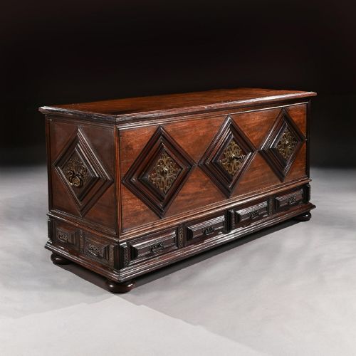 fig 2. A dark mahogany Portuguese colonial chest featuring three raised diamond-moulded panels with central pierced brass mounts above a row of lower drawers.