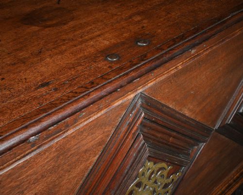 fig 3. A dark mahogany Portuguese colonial chest featuring three raised diamond-moulded panels with central pierced brass mounts above a row of lower drawers.