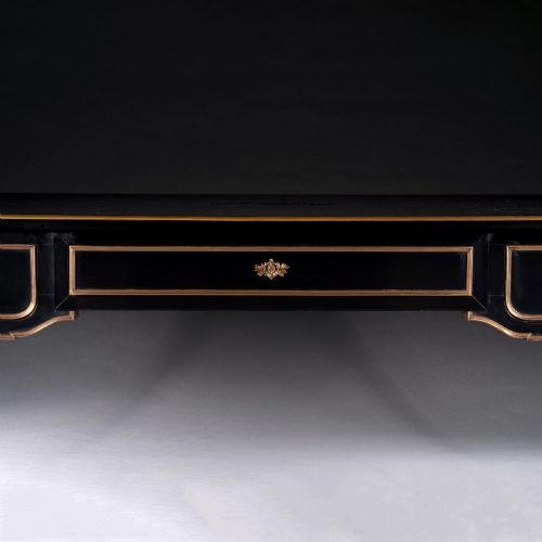 fig 1. A late nineteenth-century French ebonised writing desk featuring gilt mouldings, three frieze drawers, and slender fluted tapered legs.