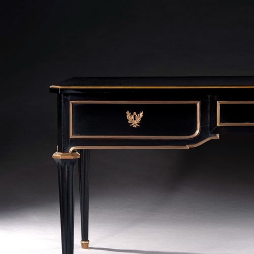 fig 2. A late nineteenth-century French ebonised writing desk featuring gilt mouldings, three frieze drawers, and slender fluted tapered legs.