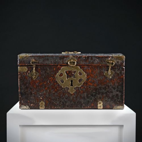 fig 1. A 17th-century dark brown leather-bound travelling box with ornate pierced brass corner mounts, side latches, central lock plate, and a top carrying handle.