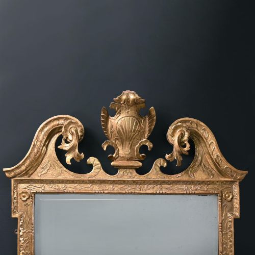 fig 1. An 18th-century George II carved gesso and giltwood wall mirror featuring a broken arch pediment with a central shell motif and foxed glass plate.