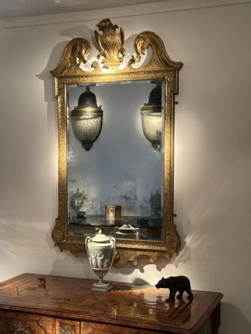 fig 4. An 18th-century George II carved gesso and giltwood wall mirror featuring a broken arch pediment with a central shell motif and foxed glass plate.