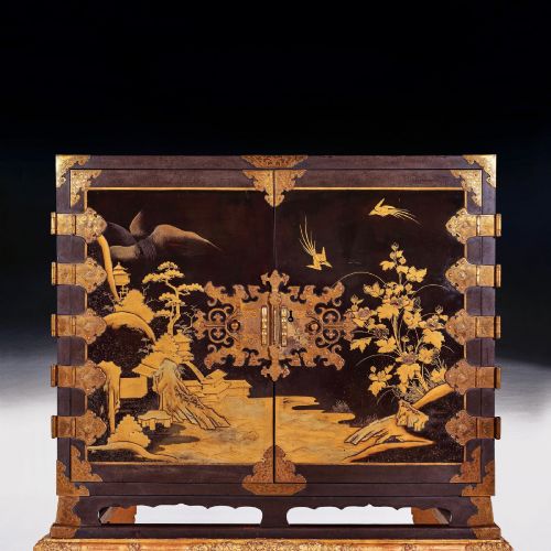fig 3. A black Japanese urushi lacquer cabinet decorated with gold landscape scenes and metal corner mounts, supported on a carved French Regence giltwood stand with cabriole legs.