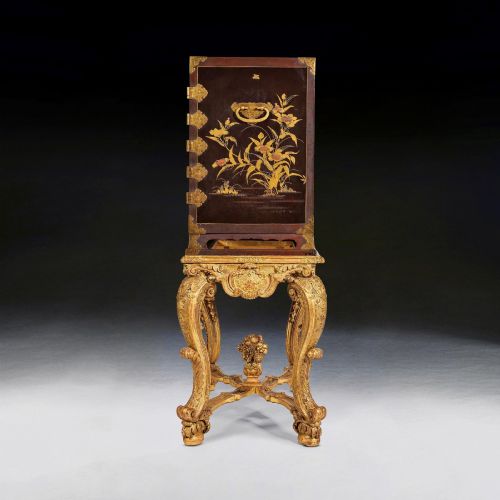 fig 5. A black Japanese urushi lacquer cabinet decorated with gold landscape scenes and metal corner mounts, supported on a carved French Regence giltwood stand with cabriole legs.