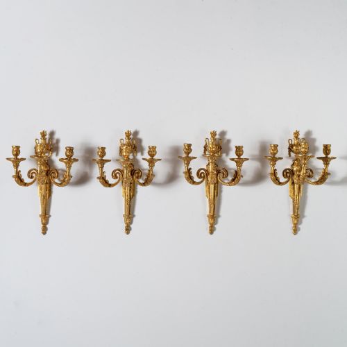 fig 2. A set of four French Louis XV style gilded bronze wall lights, each featuring three scrolling foliate arms supporting candle sockets and an urn finial backplate.