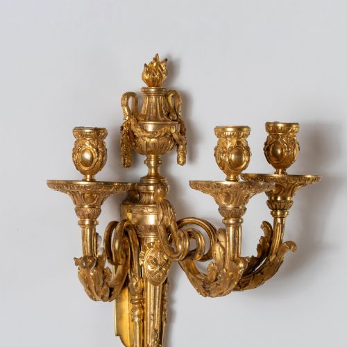 fig 5. A set of four French Louis XV style gilded bronze wall lights, each featuring three scrolling foliate arms supporting candle sockets and an urn finial backplate.