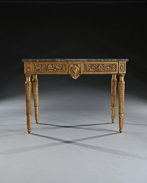 fig 3. An 18th-century Italian Neoclassical console table featuring a grey veined marble top, an intricate giltwood frieze with a central carved mask, and fluted legs.