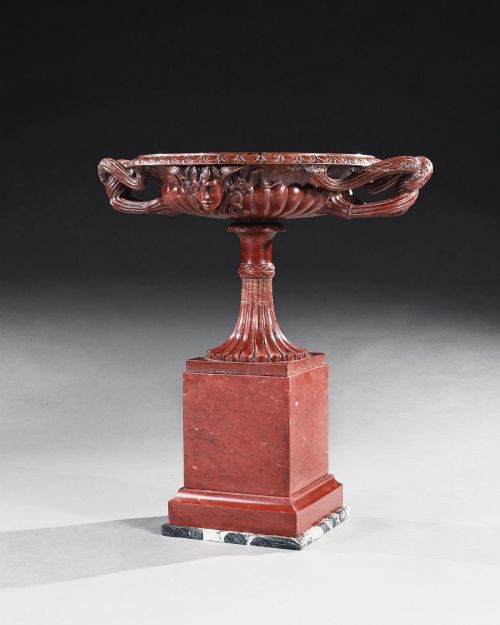 fig 2. A carved deep red Rosso Antico marble tazza featuring serpent handles, a Medusa mask motif, and a fluted stem set upon a square pedestal base.
