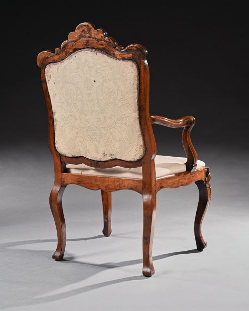 fig 3. Mid-18th-century Italian Rococo carved walnut armchair featuring cabriole legs, curved armrests, an ornate carved mask crest rail, and exposed traditional back padding.
