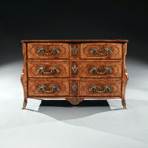 fig 1. An 18th-century French Regence commode crafted from burr maple veneer featuring three drawers with detailed gilt-bronze handles, keyhole escutcheons, and foot mounts.
