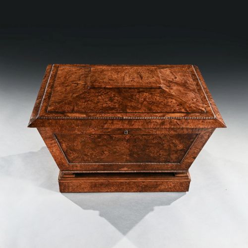 fig 3. A Regency period sarcophagus-form cellarette crafted from burr pollard oak timber featuring a hinged lid, bead moulding, and a plinth base.