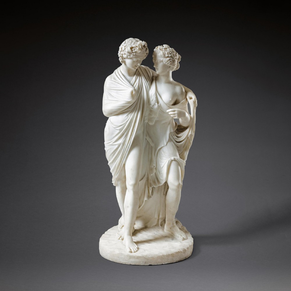 An early 19th-century Italian carved white marble sculpture depicting the classical mythological figures of Bacchus and Ariadne standing together on an oval base.