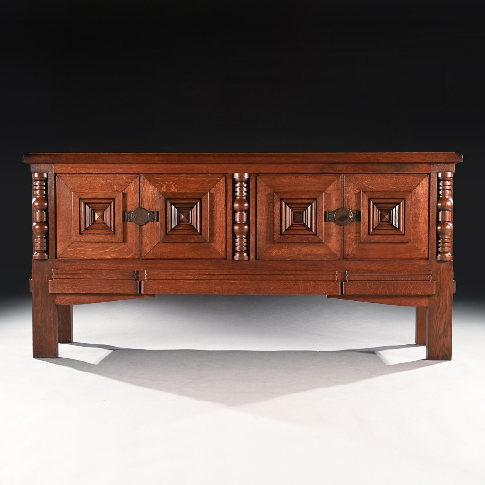 A mid-20th-century French Art Deco solid oak sideboard featuring four cabinet doors with raised geometric pyramid motifs and turned wood accents.