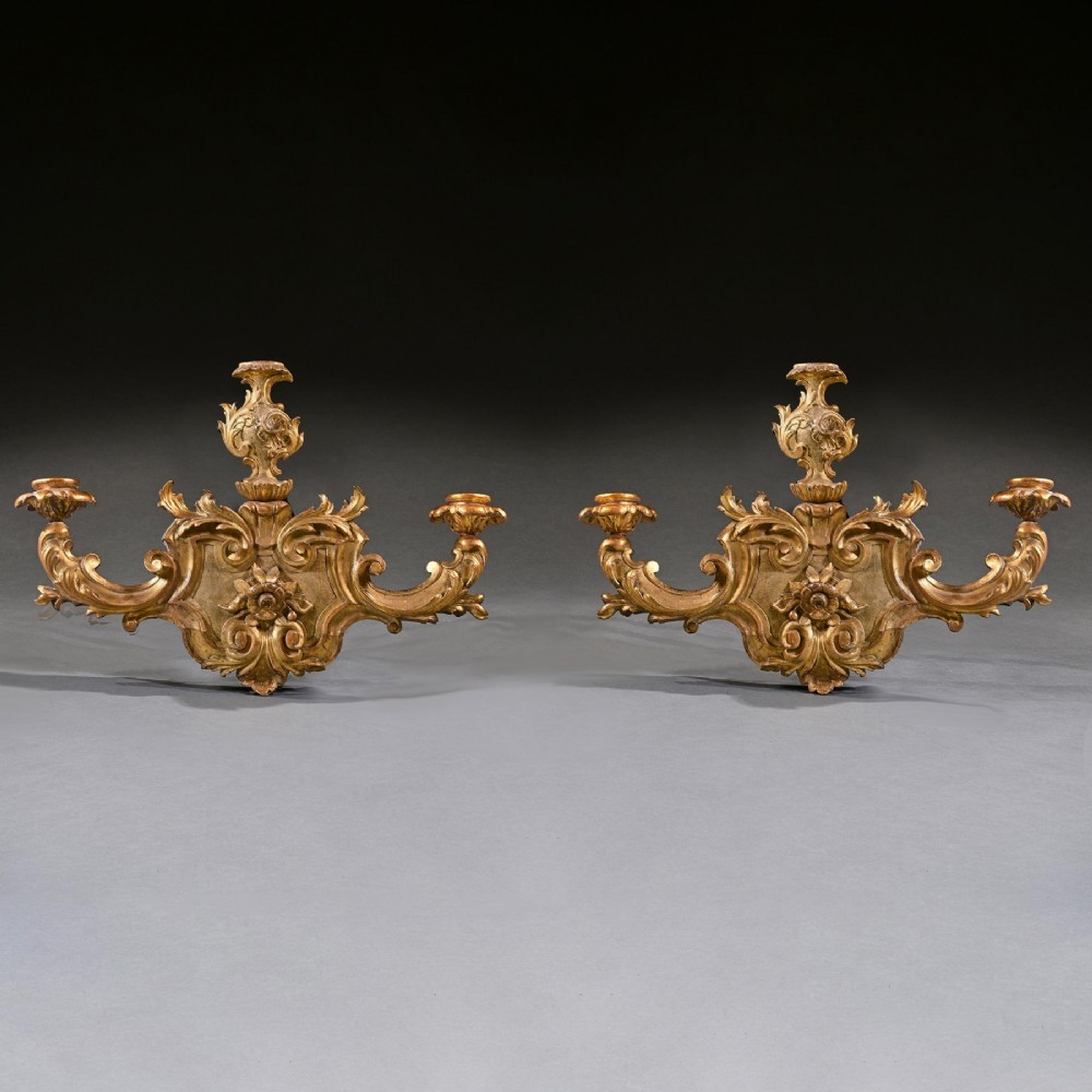 A pair of 18th-century Venetian carved giltwood wall sconces decorated with Rococo scrollwork, central urn finials, and candle nozzles. View III