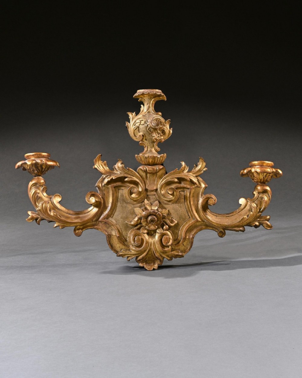 A pair of 18th-century Venetian carved giltwood wall sconces decorated with Rococo scrollwork, central urn finials, and candle nozzles. View IV