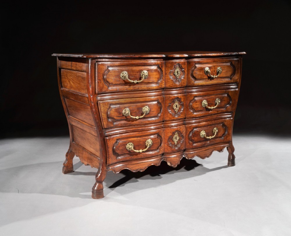 A mid-18th-century Louis XV French provincial chestnut commode featuring a bombe profile, three carved drawers, and brass hardware. View II