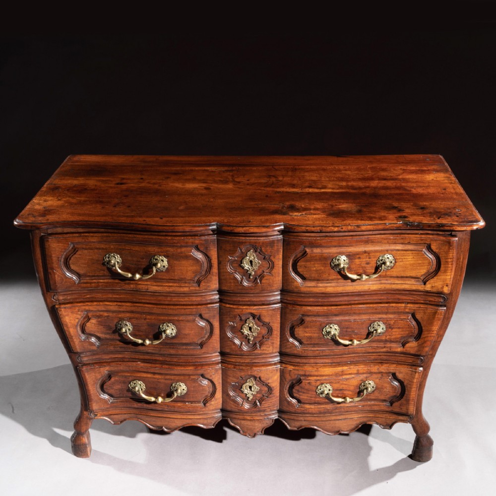 A mid-18th-century Louis XV French provincial chestnut commode featuring a bombe profile, three carved drawers, and brass hardware. View XIII