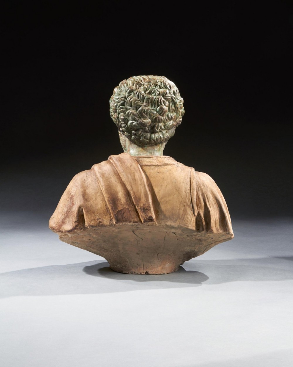 A pair of late nineteenth-century terracotta portrait busts depicting Roman Emperors Marcus Aurelius and Caracalla with verdigris-tinted heads and draped garments. View V