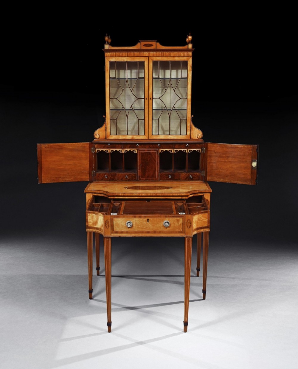 An 18th-century George III satinwood writing cabinet with a glazed upper bookcase, oval inlaid cupboard doors, and slender tapered legs. View VI
