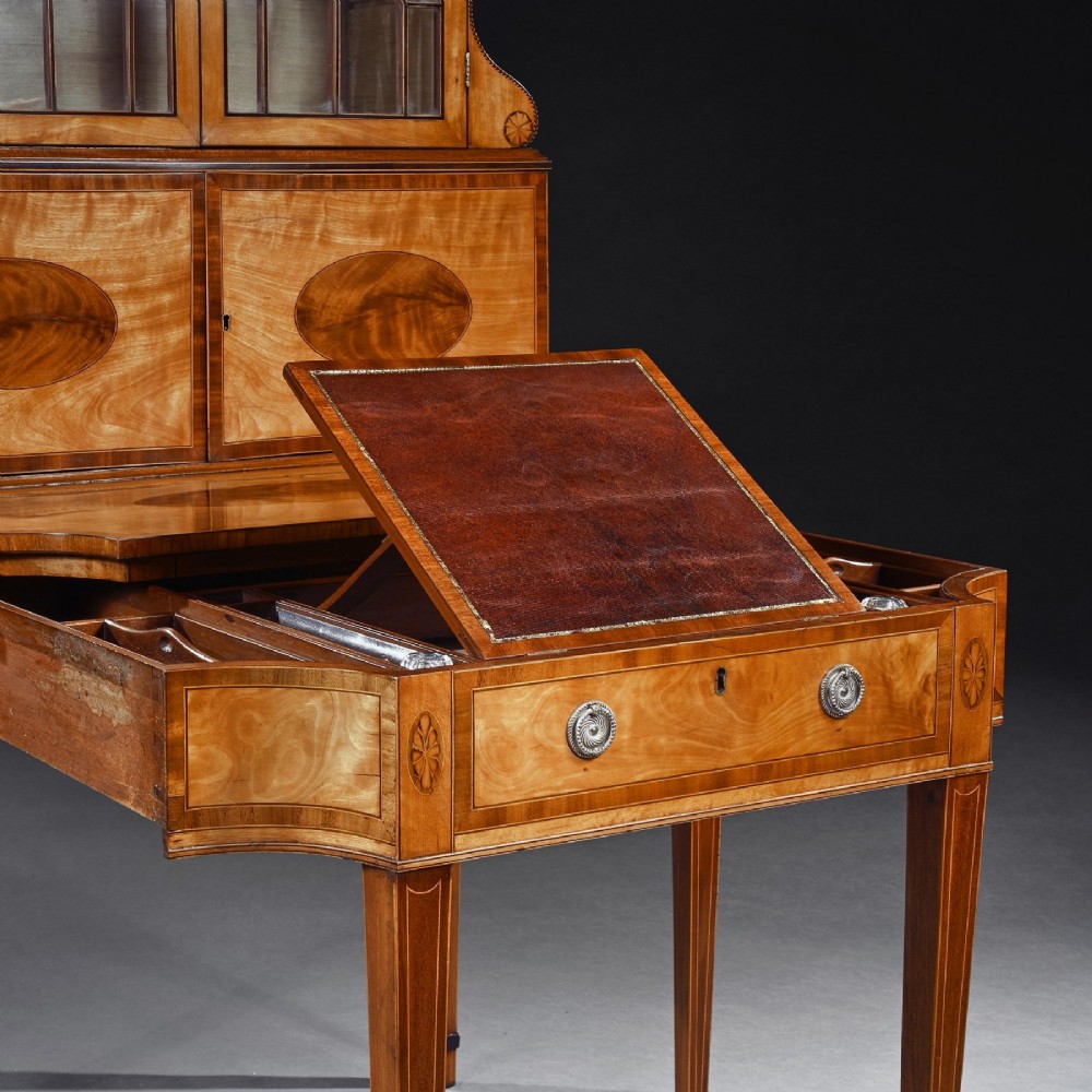 An 18th-century George III satinwood writing cabinet with a glazed upper bookcase, oval inlaid cupboard doors, and slender tapered legs. View VIII