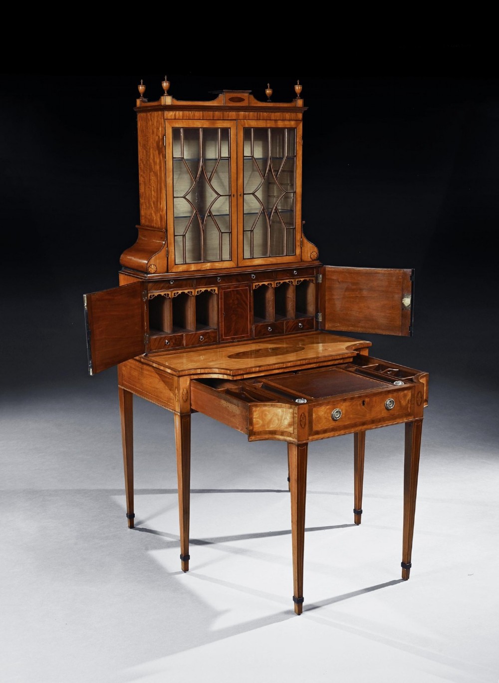 An 18th-century George III satinwood writing cabinet with a glazed upper bookcase, oval inlaid cupboard doors, and slender tapered legs. View IX