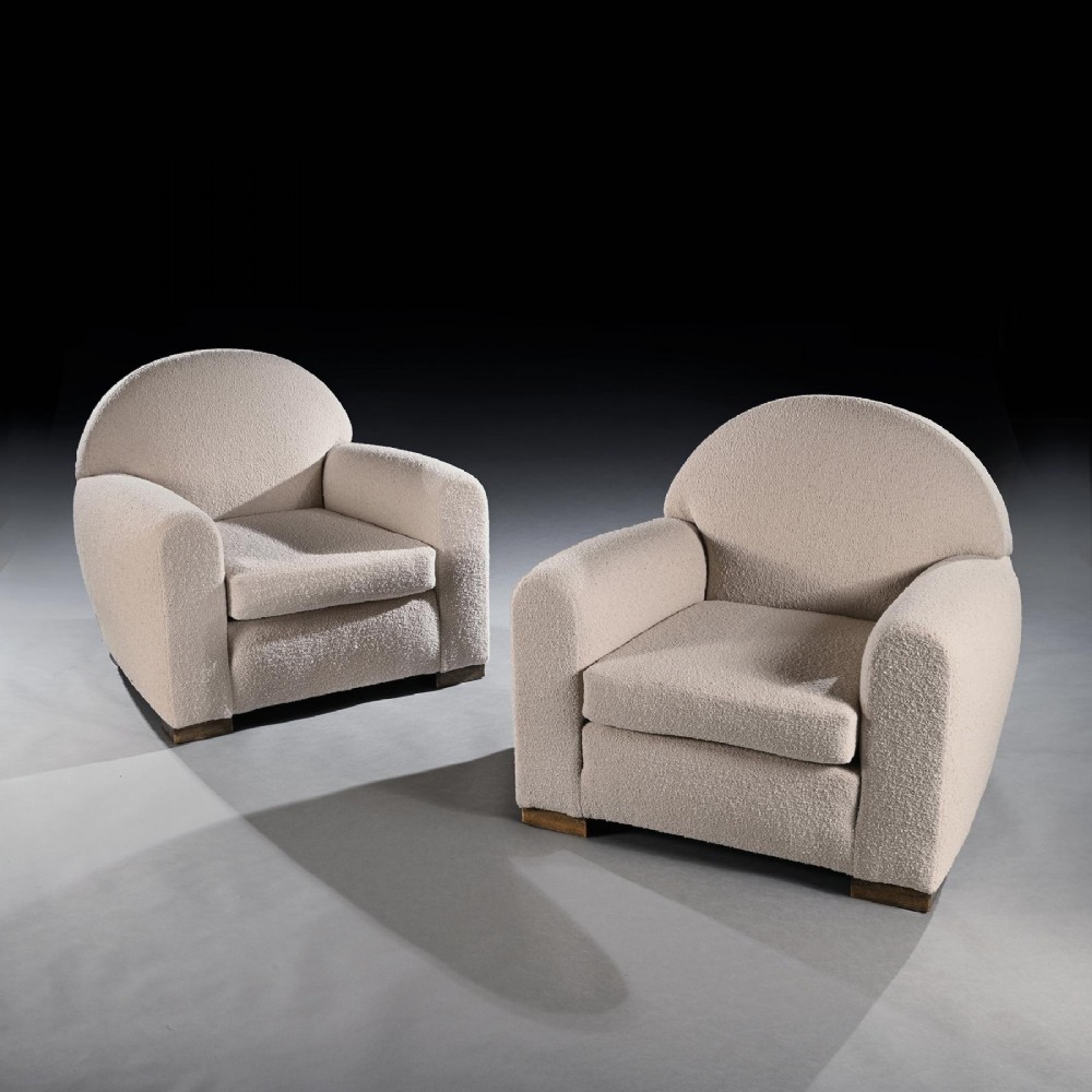 A pair of mid-twentieth-century French club armchairs upholstered in cream boucle fabric with rounded backrests and low wooden block feet. View II