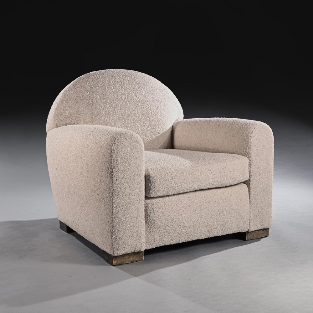 A pair of mid-twentieth-century French club armchairs upholstered in cream boucle fabric with rounded backrests and low wooden block feet. View IV